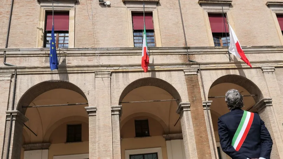 Gnassi davanti al municipio con le bandiere abbassate
