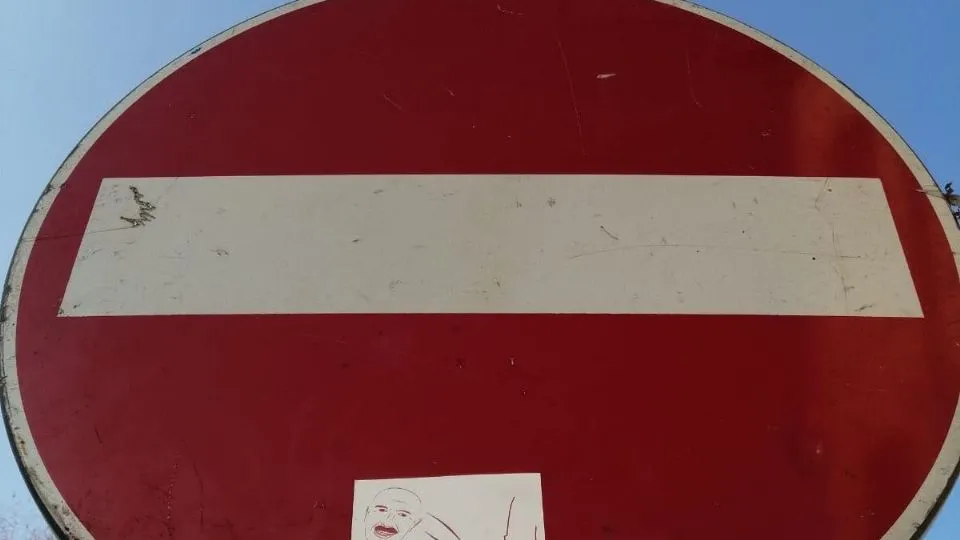 Uno degli adesivi attaccato su un cartello stradale