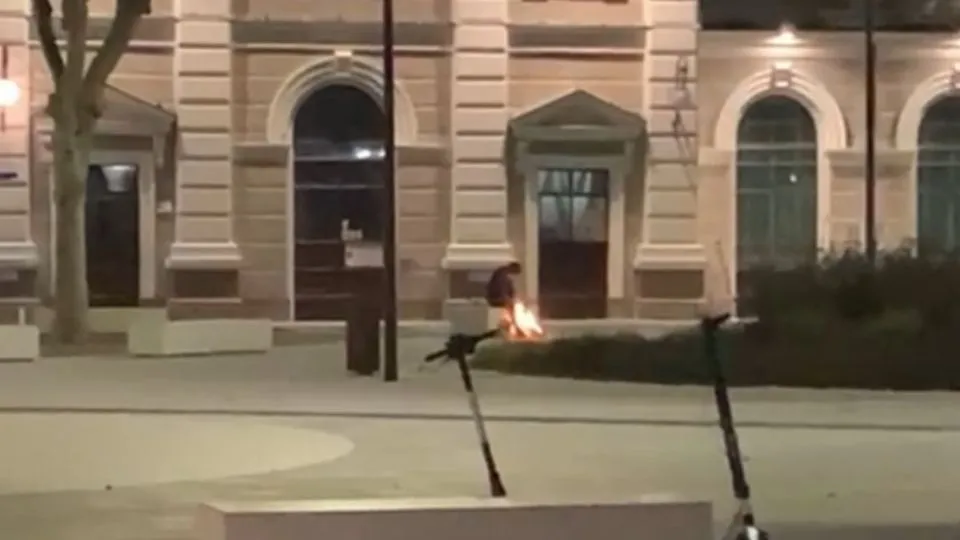 Un uomo accende un fuoco davanti alla stazione di Rimini