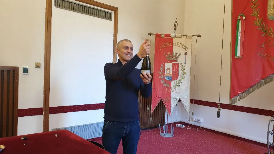 il sindaco di Rimini stappa una bottiglia di spumante
