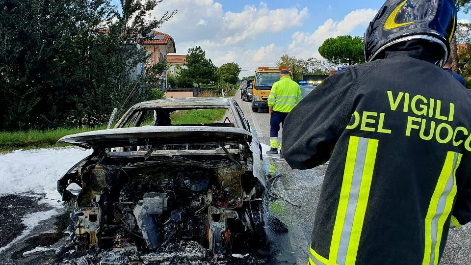 L’auto distrutta e l’intervento dei vigili del fuoco (foto Adriapress)
