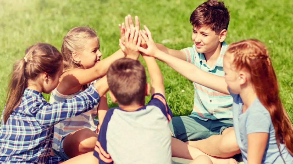 group of happy kids making high five outdoors
