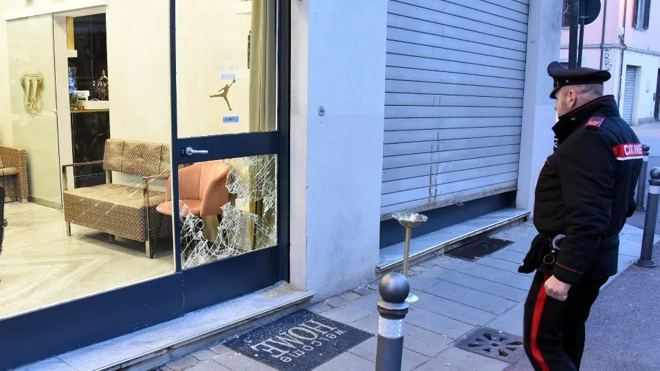 la vetrata della barberia sfondata e un carabiniere (foto Migliorini)
