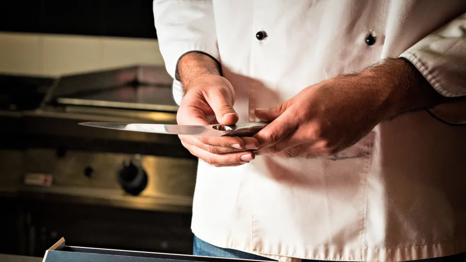 un cuoco con un coltello in mano (foto pexels)